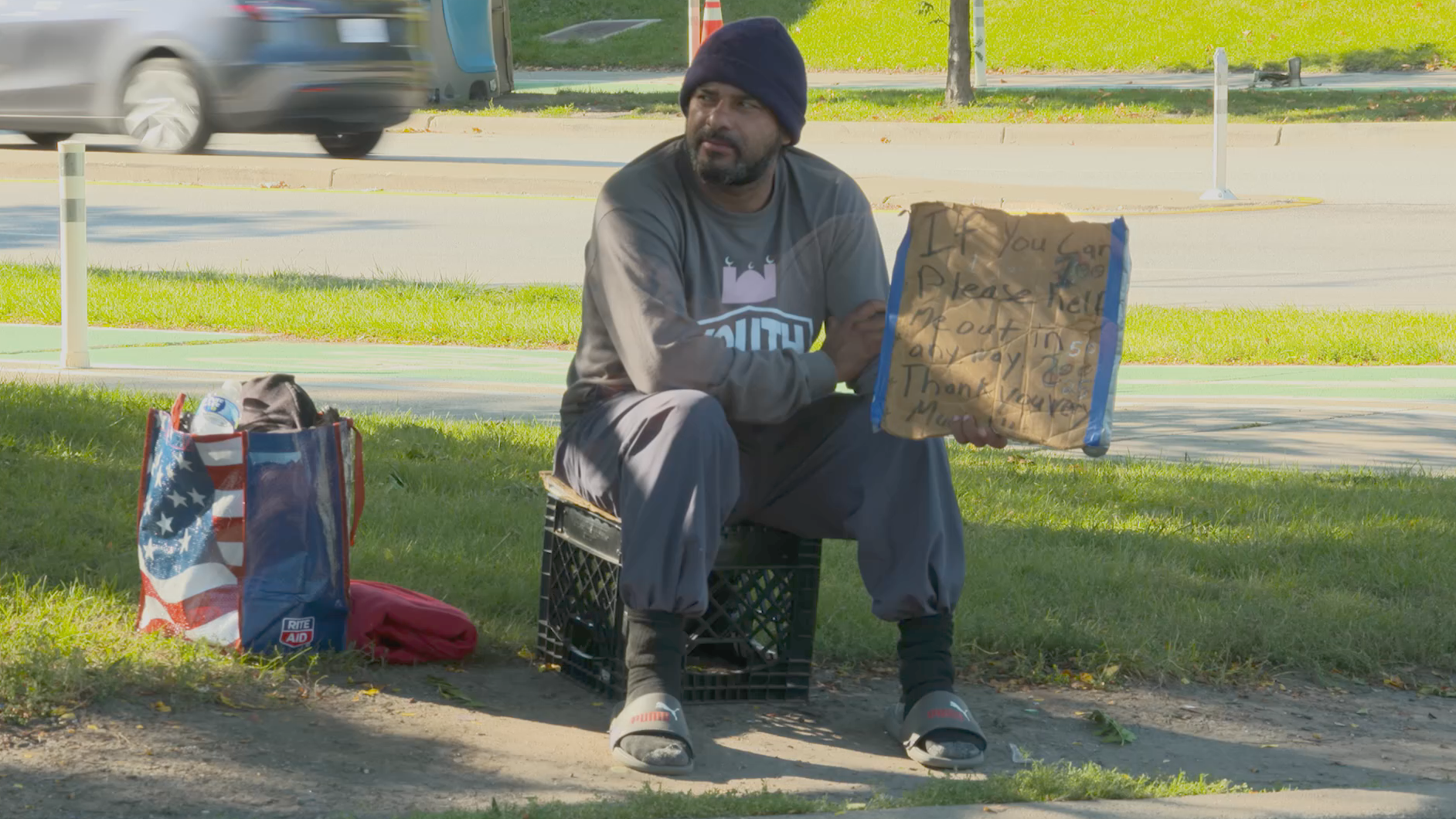 Modal Image Opens to lightbox video - A homeless person with a sign