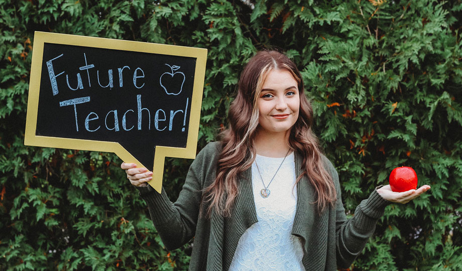 Sydney Hamilton stands with an apple and a sign that says future teacher
