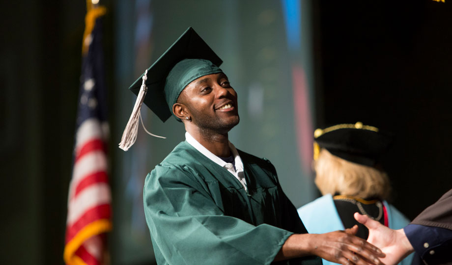 student holding a diploma at graduation