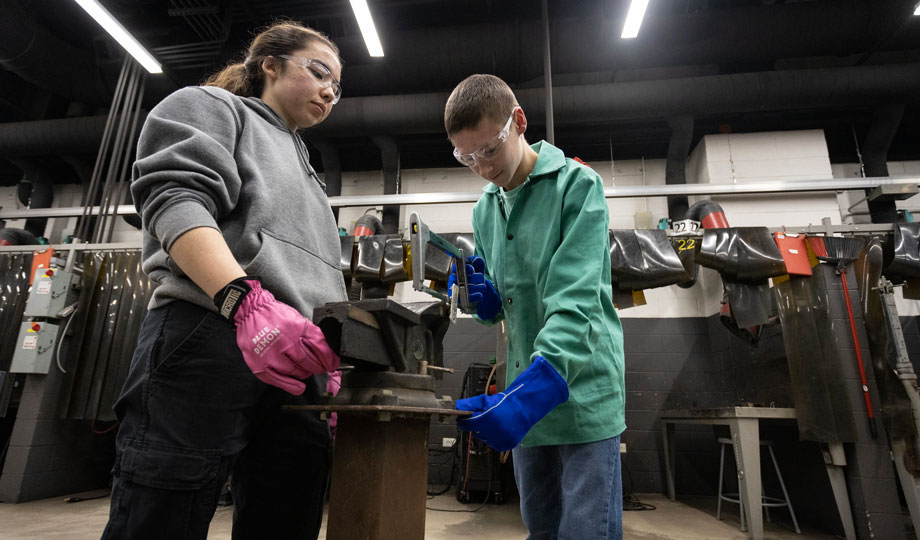 Two Boy Scouts use a welding machine while wearing eye and hand protectants