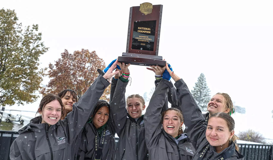 Women's Cross Country team raises trophy after win.