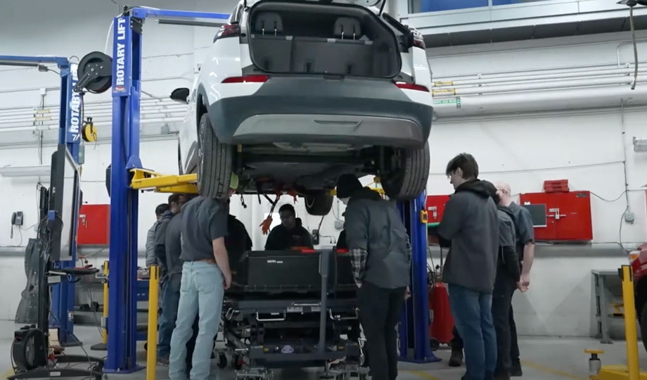 students work on taking an electric vehicle battery out of an electric car