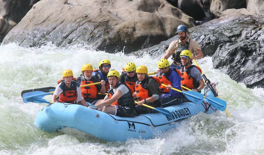 Instructor and students navigating rapids in raft.